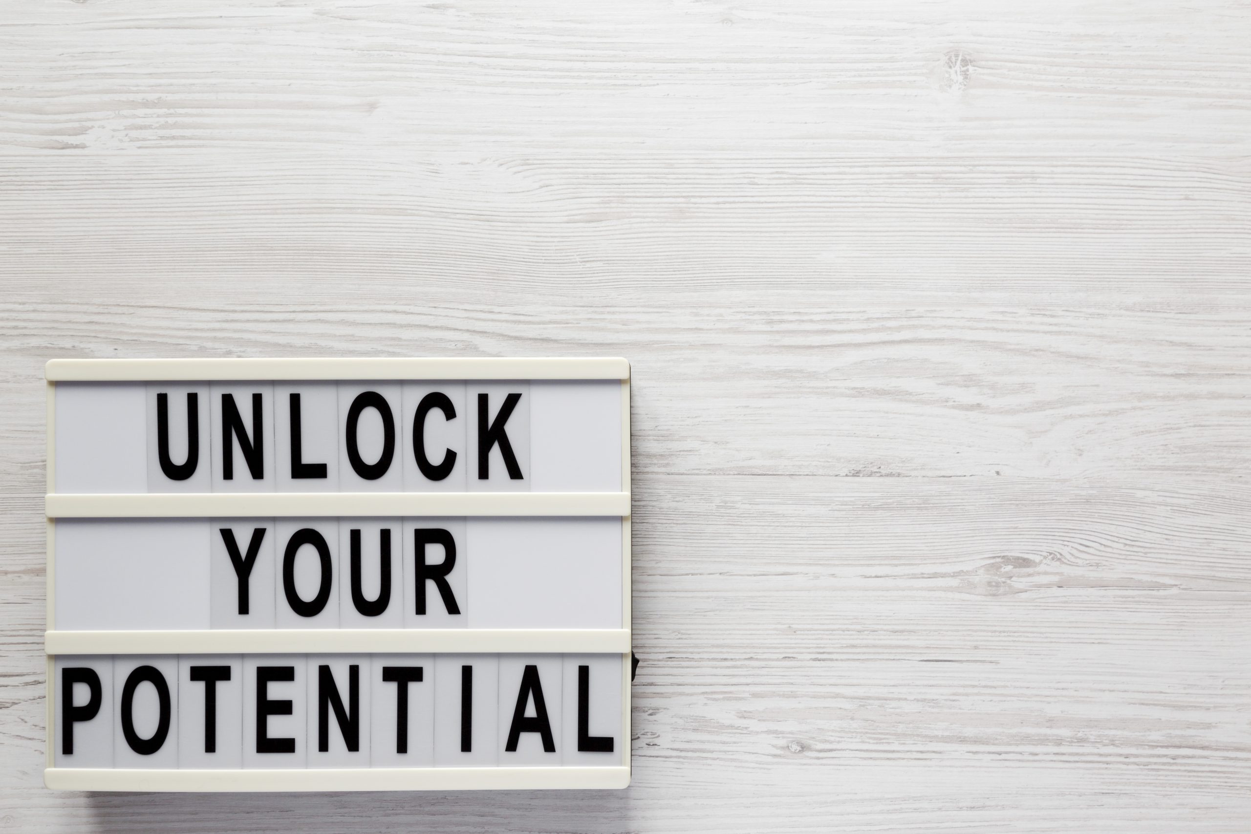 'Unlock your potential' on a lightbox on a white wooden surface,