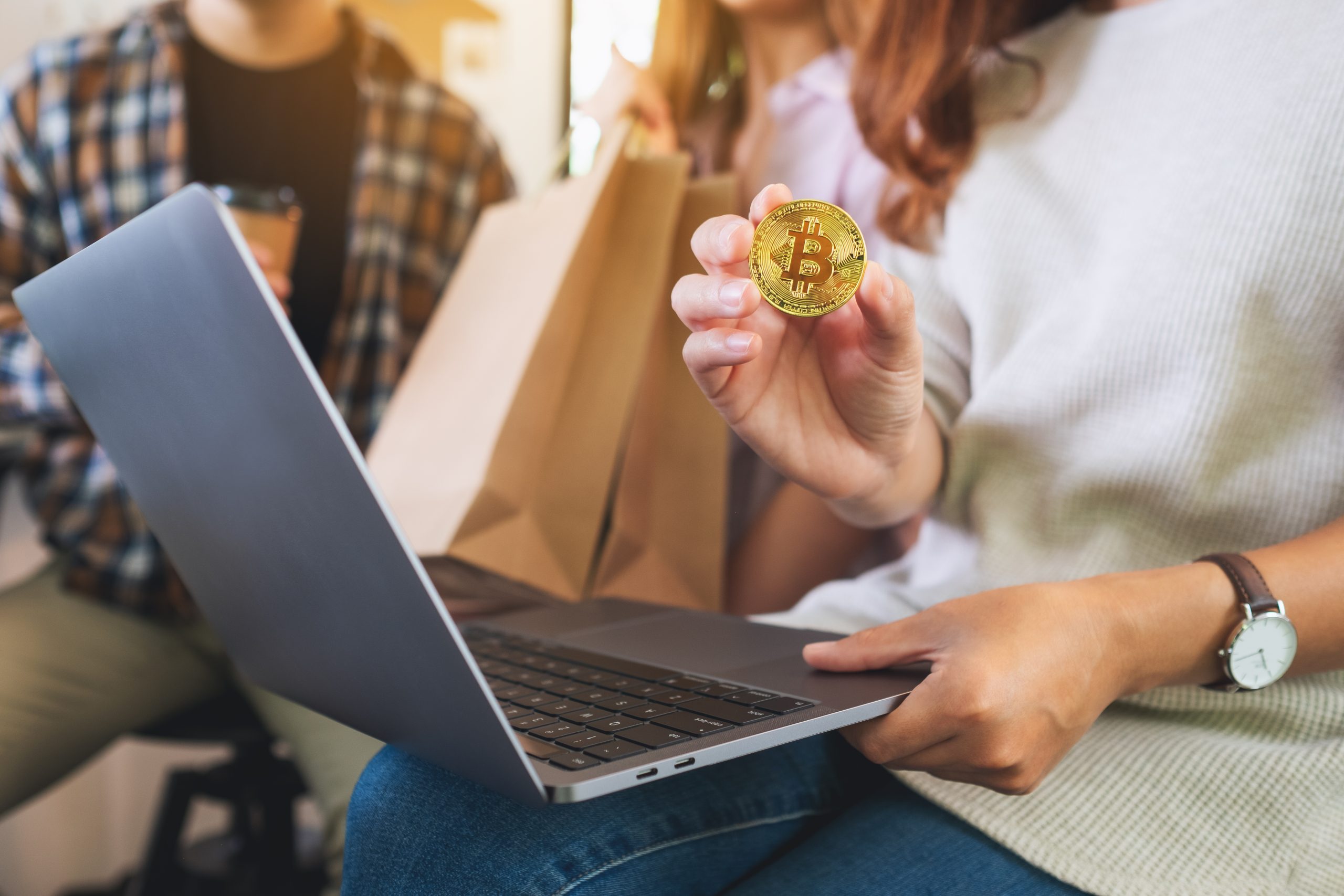 Group of young people using laptop and bitcoin for shopping onli